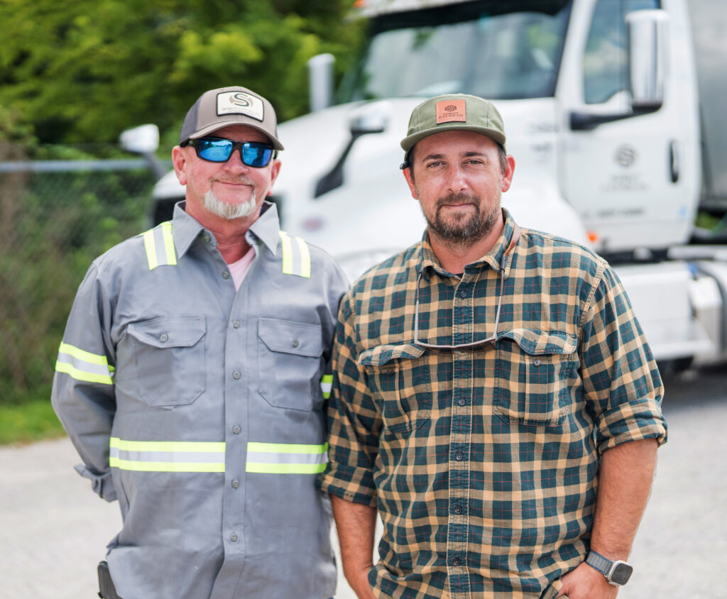 Two men outside in front of large truck